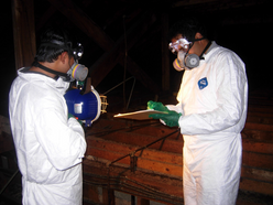 two men wearing white jumpsuits and respirators