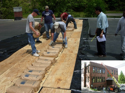 men placing sandbags on plywood boards on top of building roof